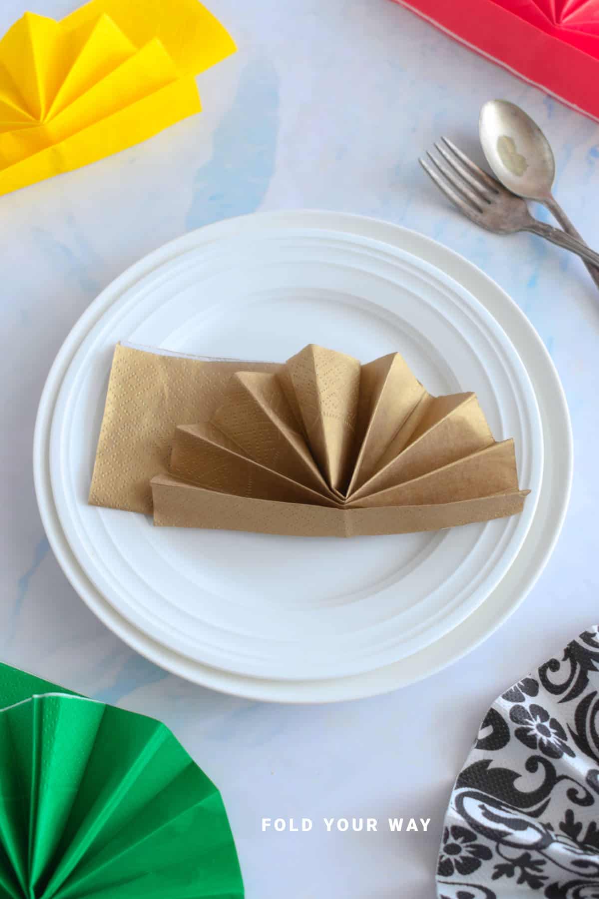 Gold napkin folded on a plate.