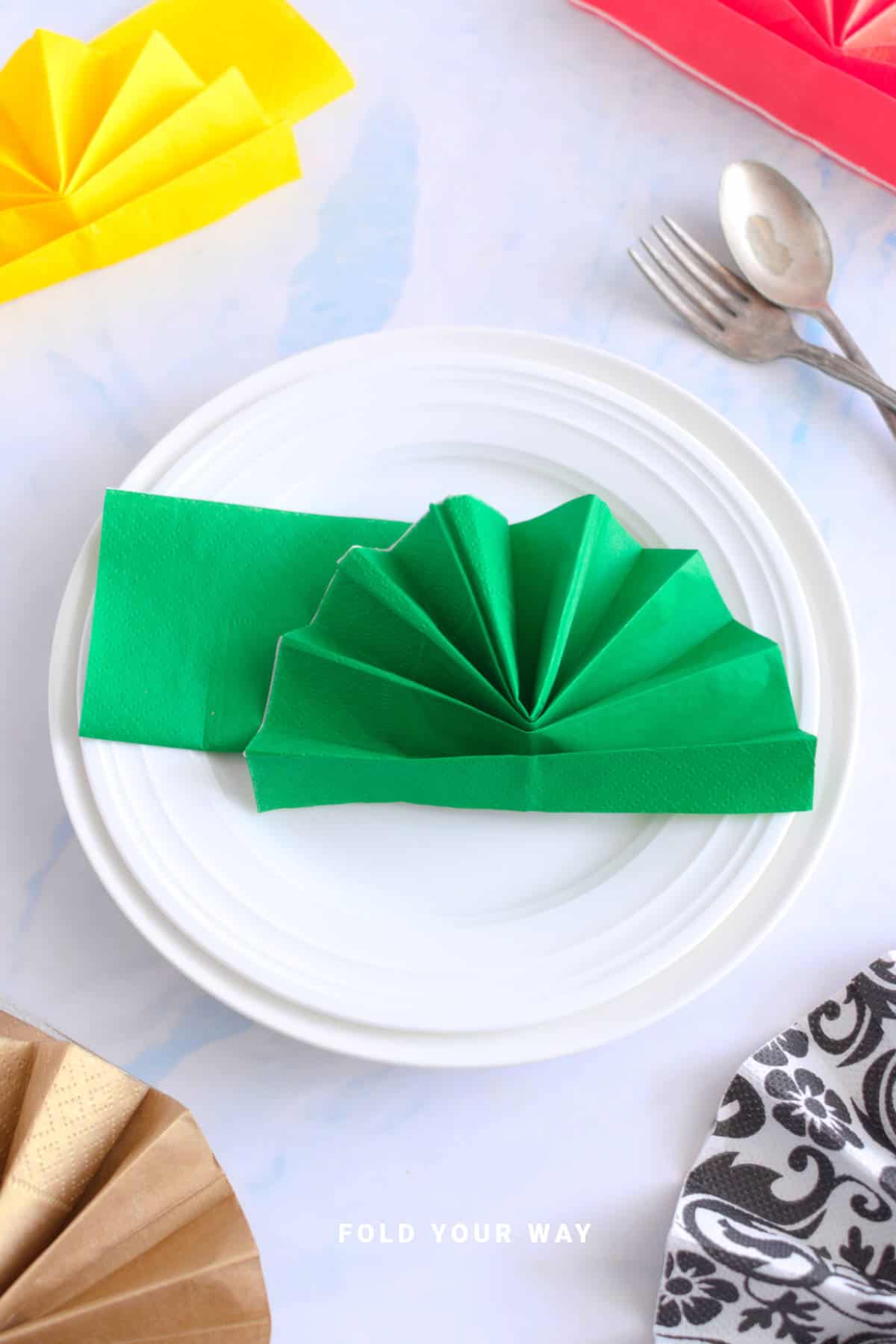 Green folded napkin on a plate.