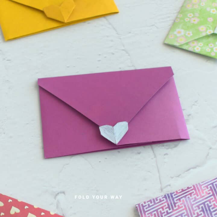 Pink origami envelope with heart closure.